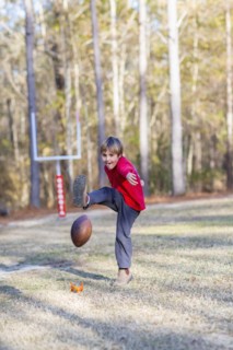 Caucasian boy kicking football in field