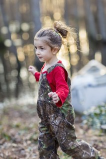 Caucasian girl wearing camouflage overalls outdoors