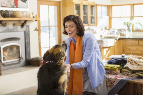 Hispanic woman petting dog in kitchen
