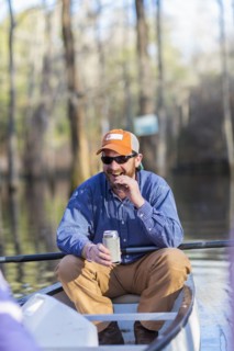 Caucasian man drinking beer in canoe on river