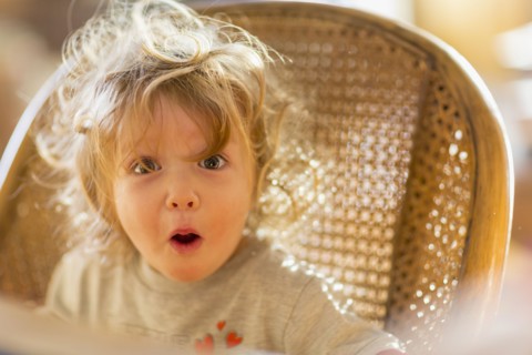 Caucasian baby boy gasping in wicker chair