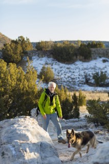 Older man and dog standing on remote rock formations
