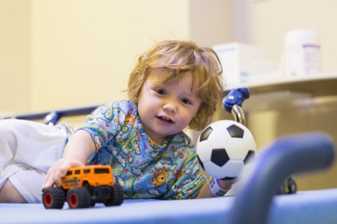 Caucasian boy playing on hospital bed