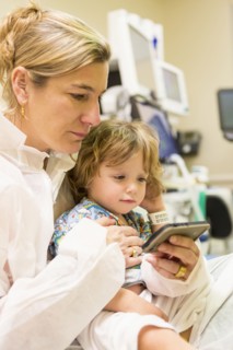 Caucasian mother and son texting on cell phone in hospital