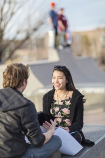 Teenage couple talking at skateboard park