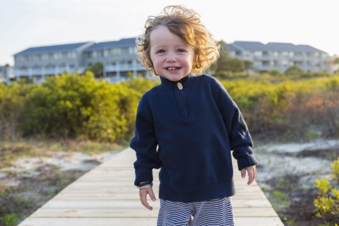 Caucasian baby boy on wooden walkway on beach