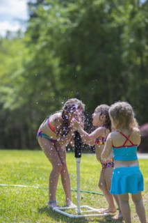Caucasian girls playing in sprinkler