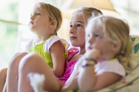 Caucasian girls watching television in armchair