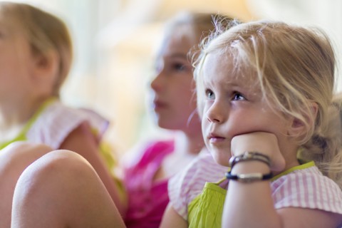 Caucasian girls watching television in armchair