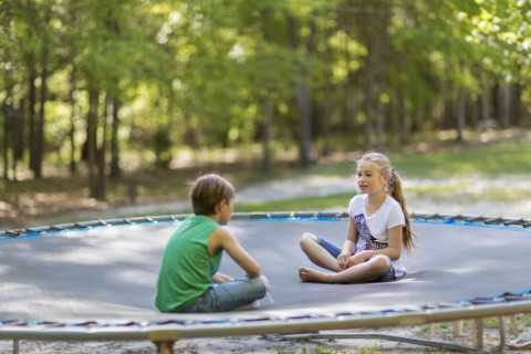 Caucasian children sitting on trampoline