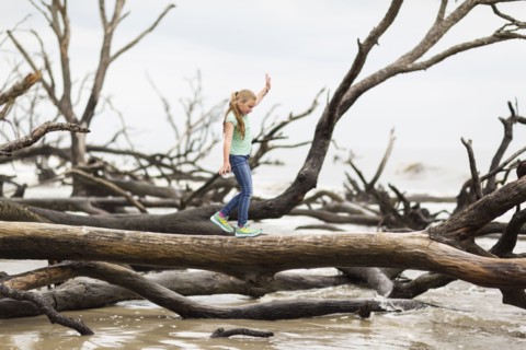 Caucasian girl walking on driftwood tree