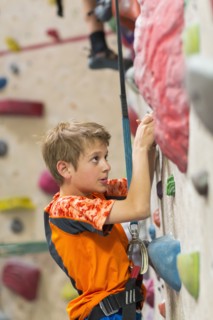 Caucasian boy climbing rock wall indoors
