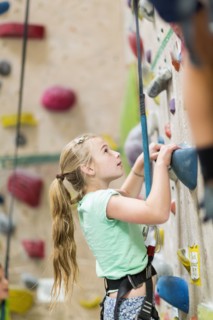 Caucasian girl climbing rock wall indoors