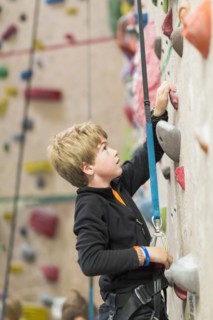 Boy climbing rock wall indoors