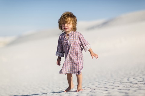 Caucasian baby boy walking on desert sand dune