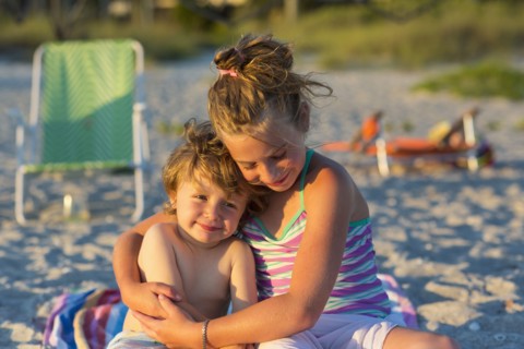 Caucasian children hugging on beach