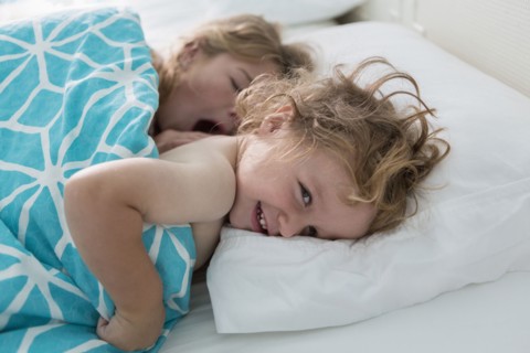 Caucasian brother and sister laying in bed