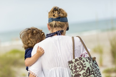 Caucasian mother carrying baby son on beach