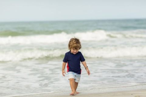 Caucasian baby boy walking on beach