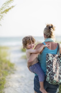 Caucasian mother carrying baby son on beach