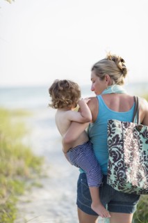 Caucasian mother carrying baby son on beach