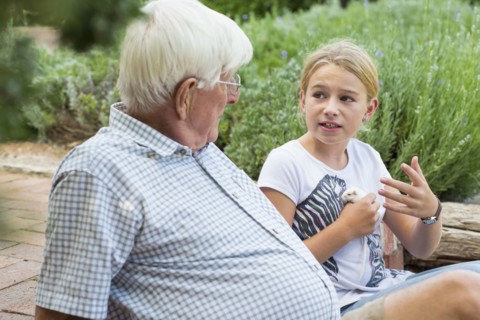 Caucasian grandfather and granddaughter talking in garden