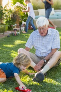 Caucasian grandfather and grandson playing on lawn