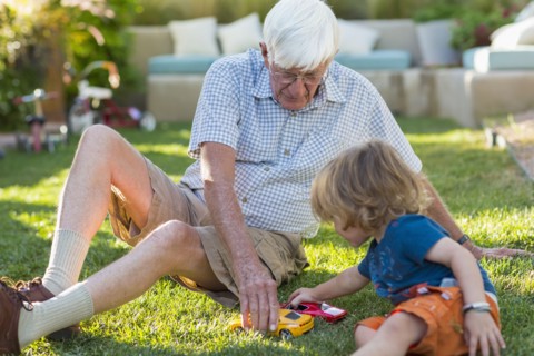 Caucasian grandfather and grandson playing on lawn