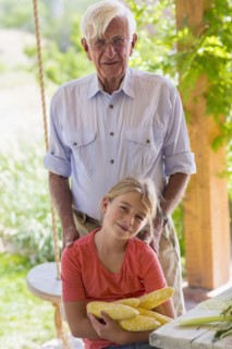 Caucasian grandfather and granddaughter shucking corn