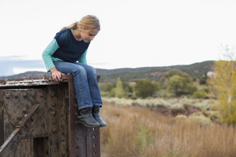 Caucasian girl sitting on structure outdoors