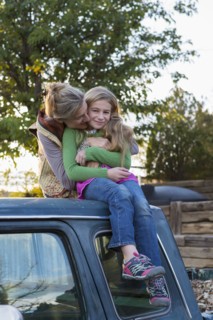 Caucasian mother hugging daughter on roof of truck
