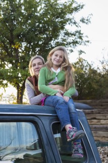 Caucasian mother and daughter hugging on truck roof