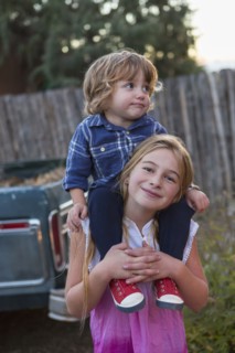 Caucasian girl carrying brother on shoulders