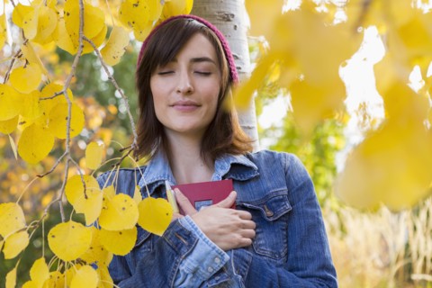 Hispanic woman holding diary in tree