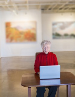 Older mixed race woman using laptop in art gallery