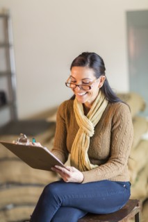 Hispanic woman writing on clipboard