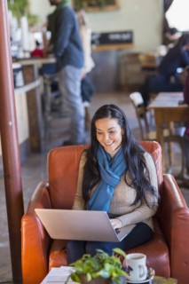 Hispanic woman using laptop in cafe