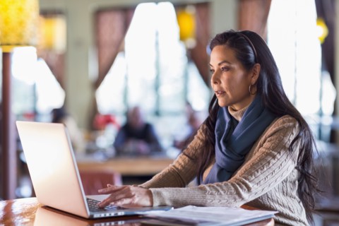 Hispanic woman using laptop in cafe