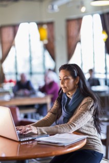 Hispanic woman using laptop in cafe
