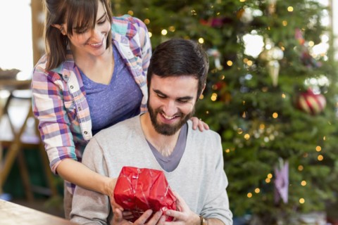 Hispanic couple exchanging Christmas gifts