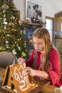 Caucasian girl decorating gingerbread house