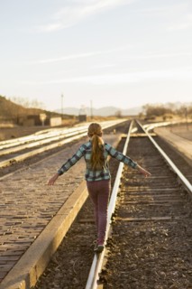 Caucasian girl balancing on train tracks