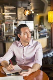 Hispanic businessman using cell phone in coffee shop