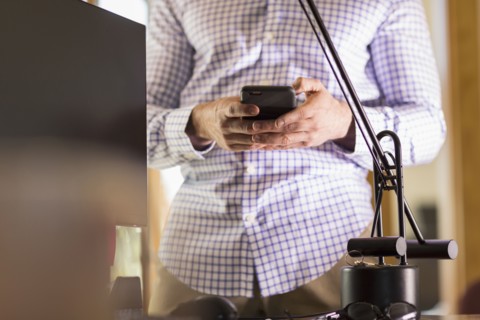 Hispanic businessman using cell phone in office