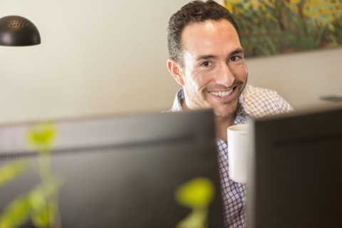 Hispanic businessman drinking coffee in office