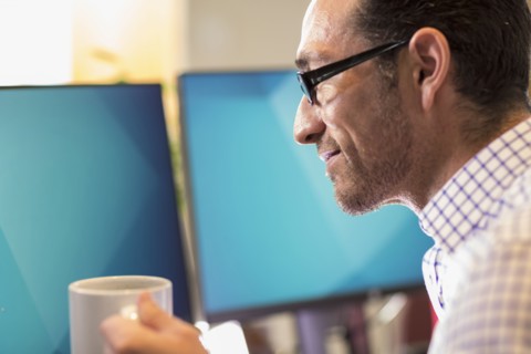 Hispanic businessman drinking coffee in office
