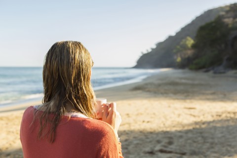 Caucasian woman drinking coffee on beach