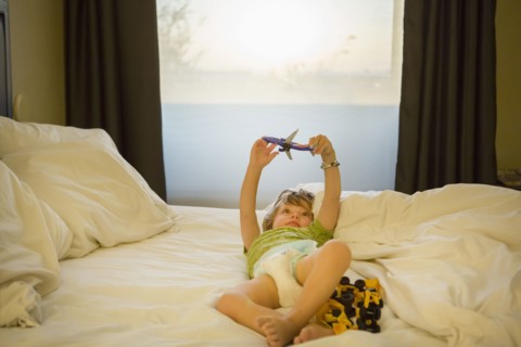 Caucasian boy playing with airplane on bed