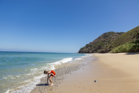 Caucasian girl examining rocks at ocean beach