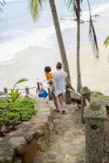 Caucasian mother carrying son descending staircase to beach